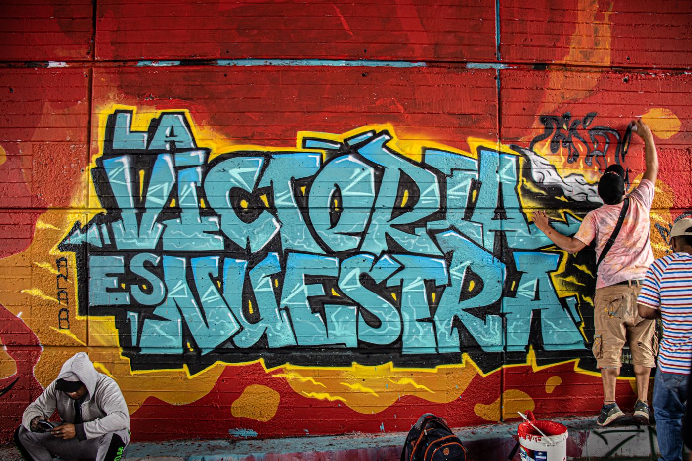 An artist painting a colorful mural on a brick wall during an outdoor arts festival