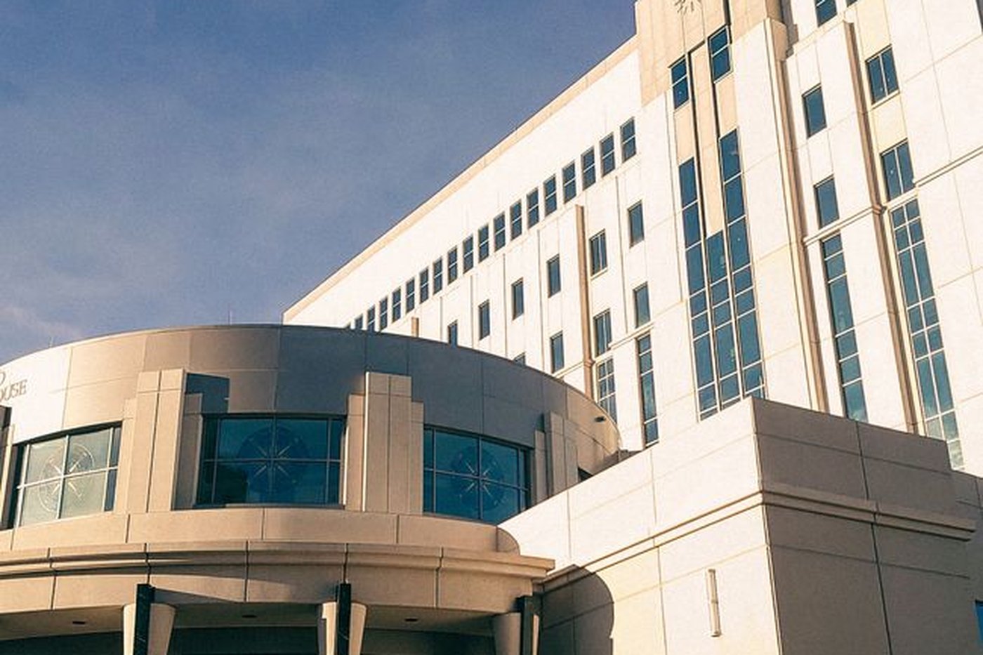 Modern government building exterior with a rounded glass entrance against a blue sky, used here as a representative image